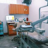 A dentist 's office with a computer and chair.