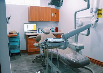 A dentist 's office with a computer and chair.