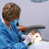 A dentist is examining the teeth of a patient.