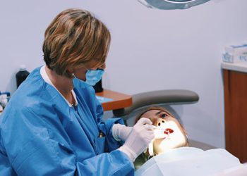 A dentist is examining the teeth of a patient.