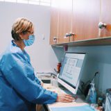 Two people in scrubs and masks working on a patient.
