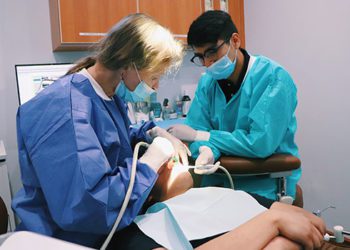 Two people in scrubs and masks working on a patient.