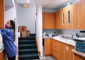 A woman standing in the kitchen of an office building.